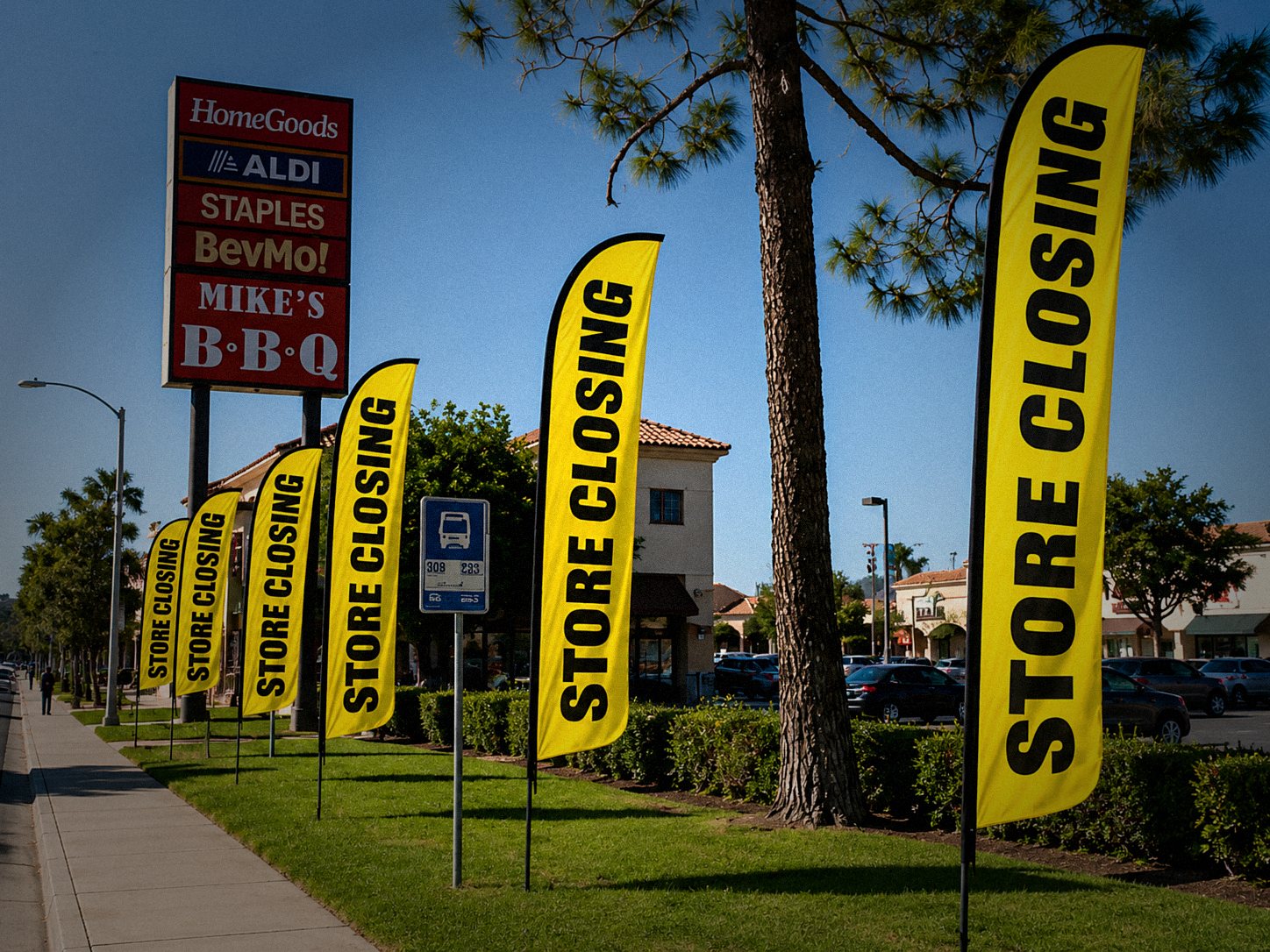 Row of yellow Store Closing feather flags lining a shopping center